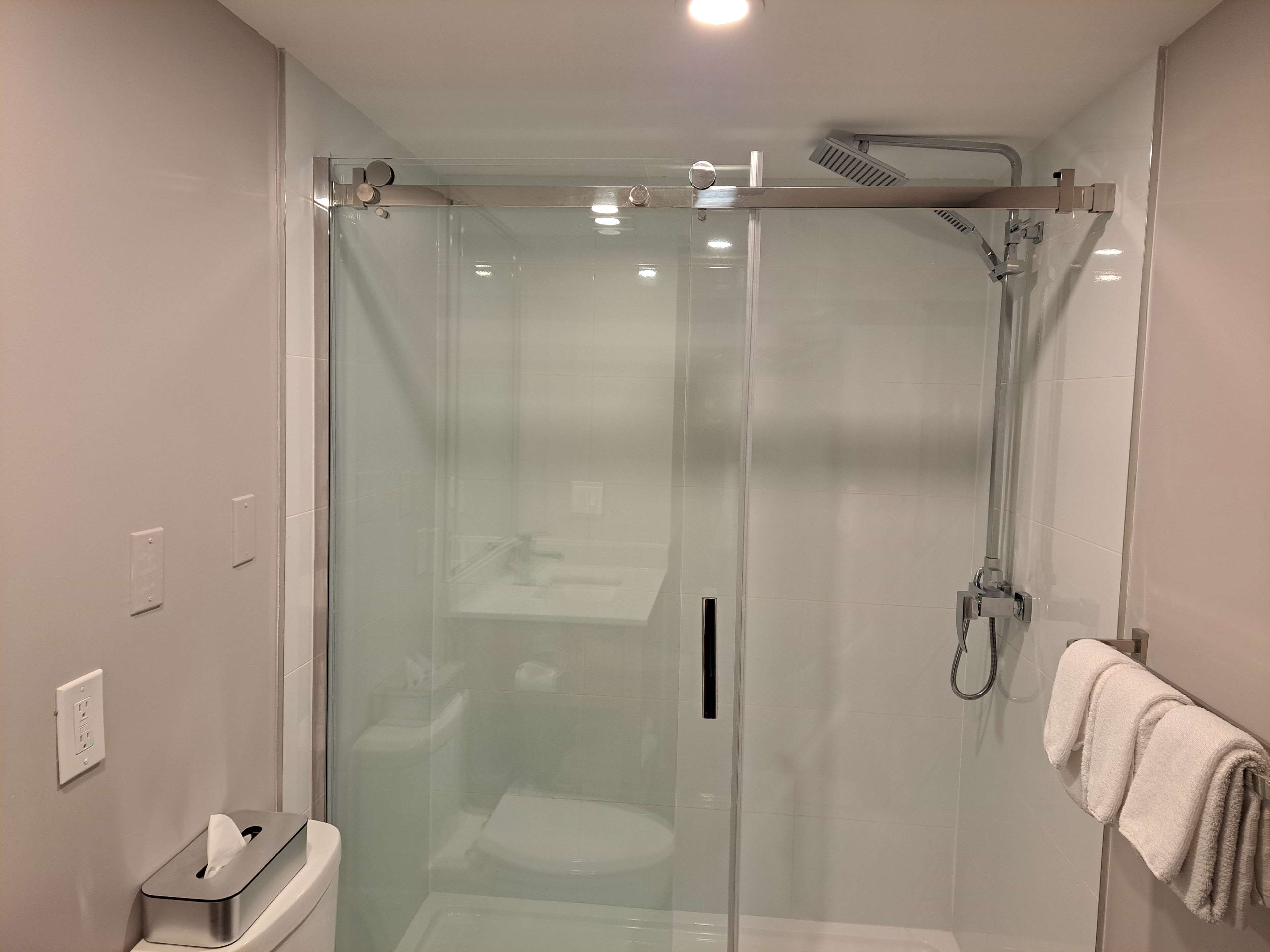 Un bagno moderno con cabina doccia in vetro, un water e un porta asciugamani.