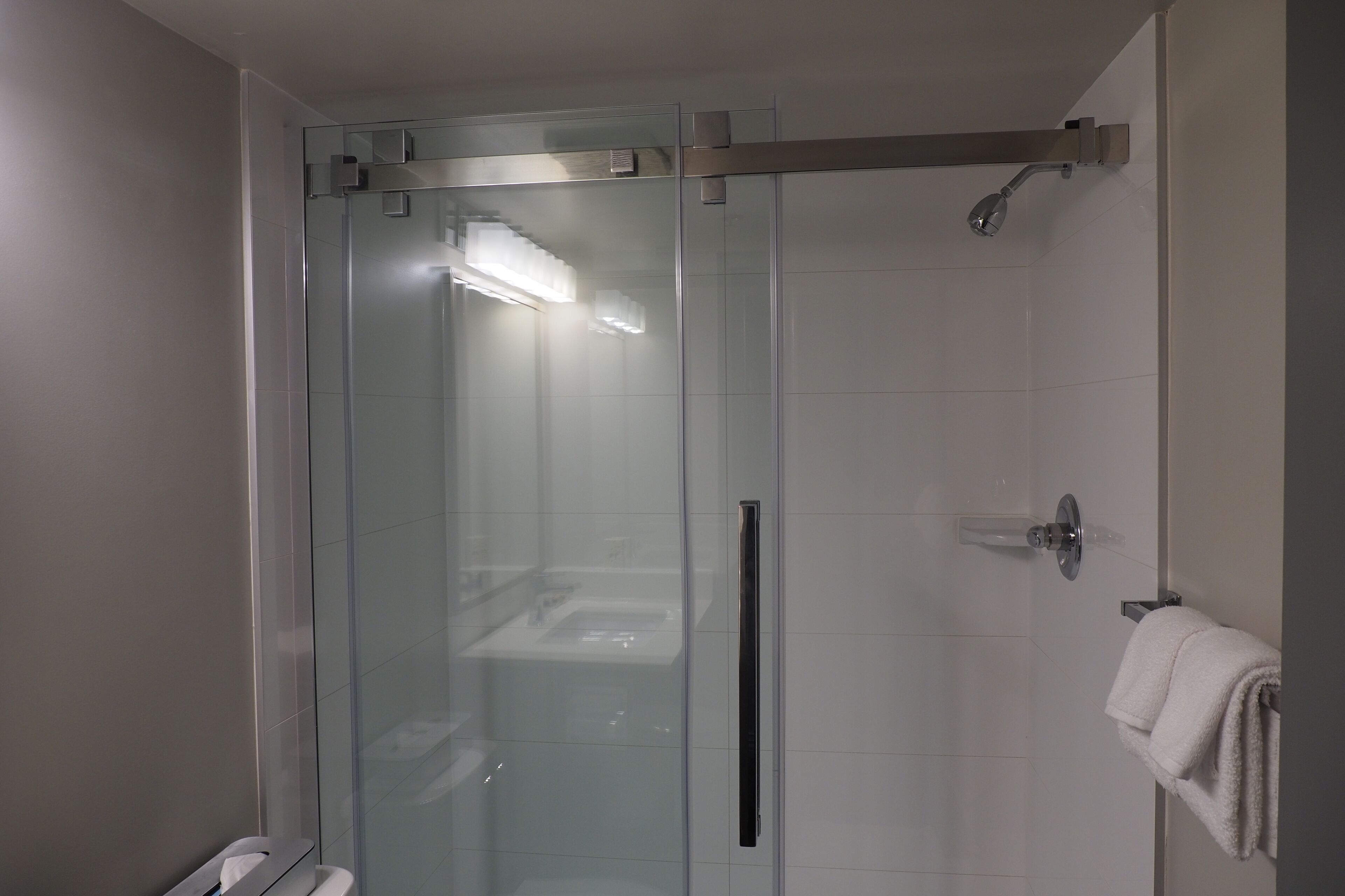 A modern bathroom with a glass-enclosed shower, a visible toilet, and a towel rack with a towel.