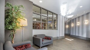 A modern waiting area with grey sofas, a large window, and a potted plant. - Best Western Plus Vancouver Airport Hotel (Vancouver)