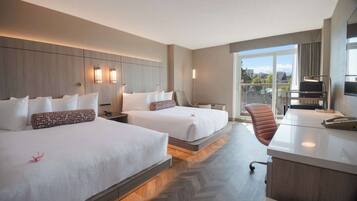 A hotel room with two beds, a desk, a chair, and a view of the city.