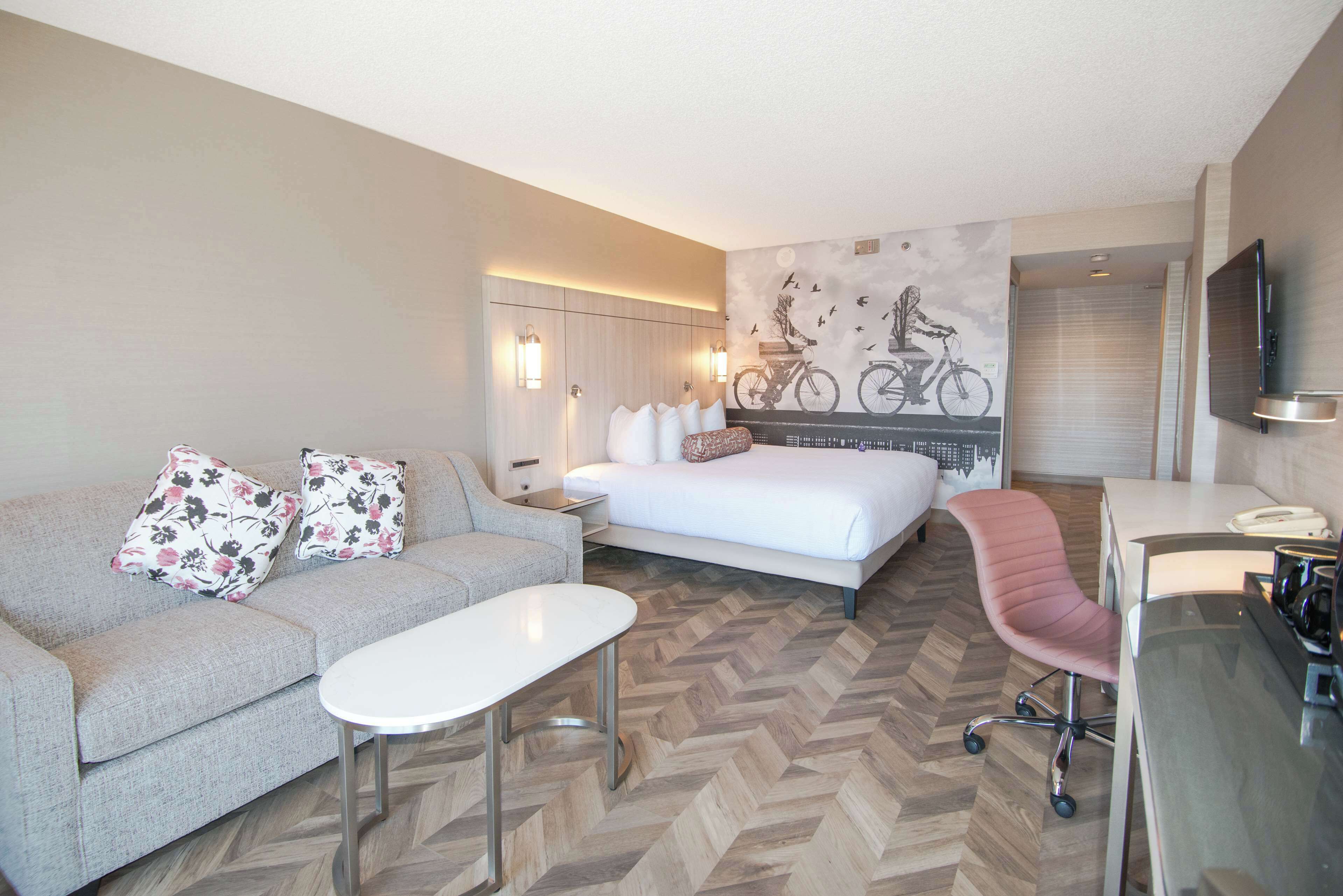 A hotel room with a bed, a sofa, a desk, and a chair.