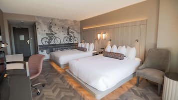 Une chambre d’hôtel avec deux lits, un bureau, une chaise et une fresque murale.