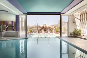 An indoor swimming pool with clear views of the cityscape through large windows. - Coast Victoria Hotel & Marina by APA (Victoria)