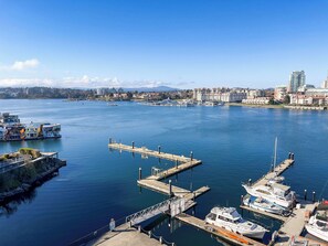 Uma marina com barcos atracados, um cais e uma paisagem urbana ao fundo.