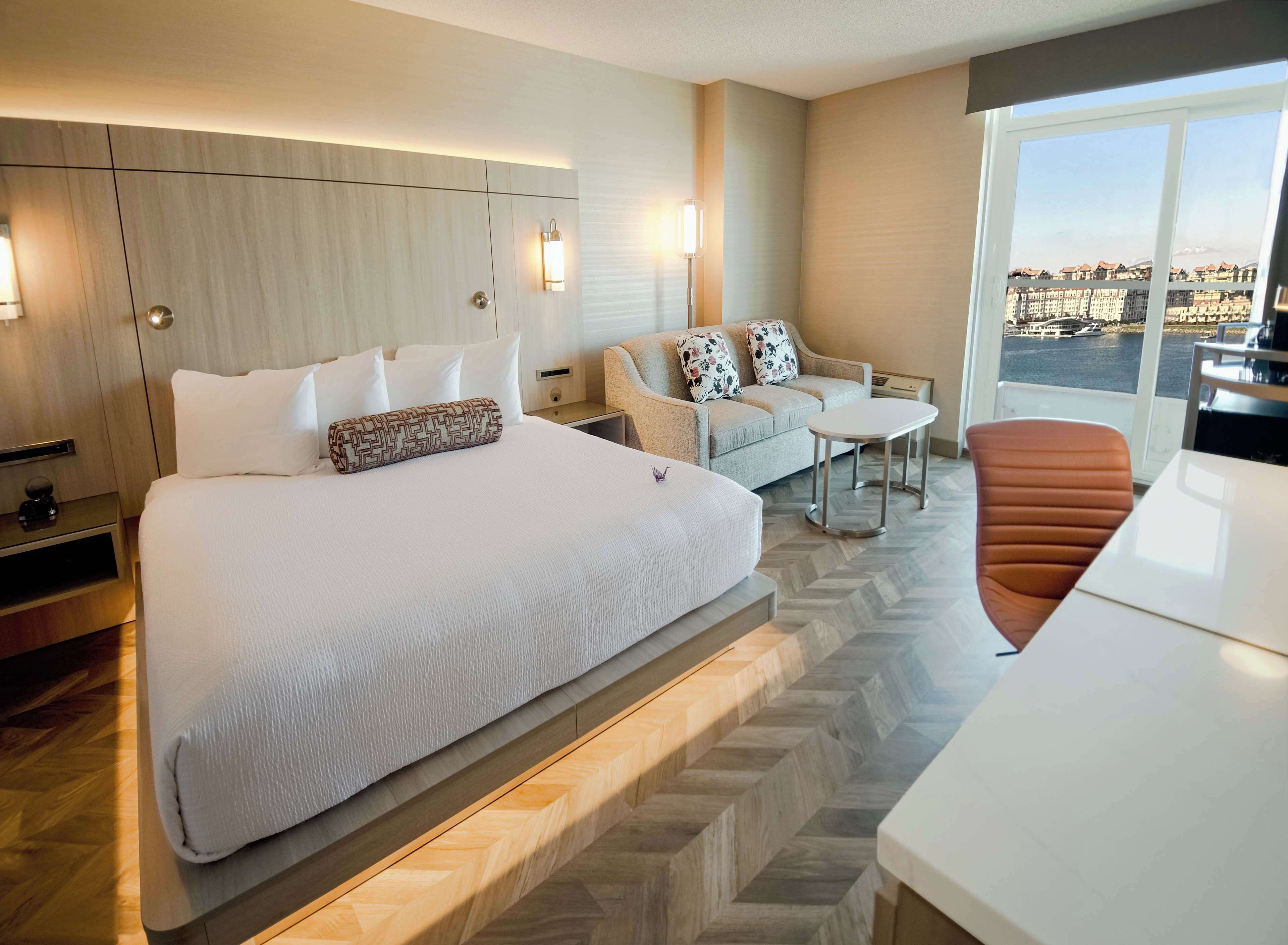 Une chambre d’hôtel avec un grand lit, un canapé, une petite table et une vue sur la ville.