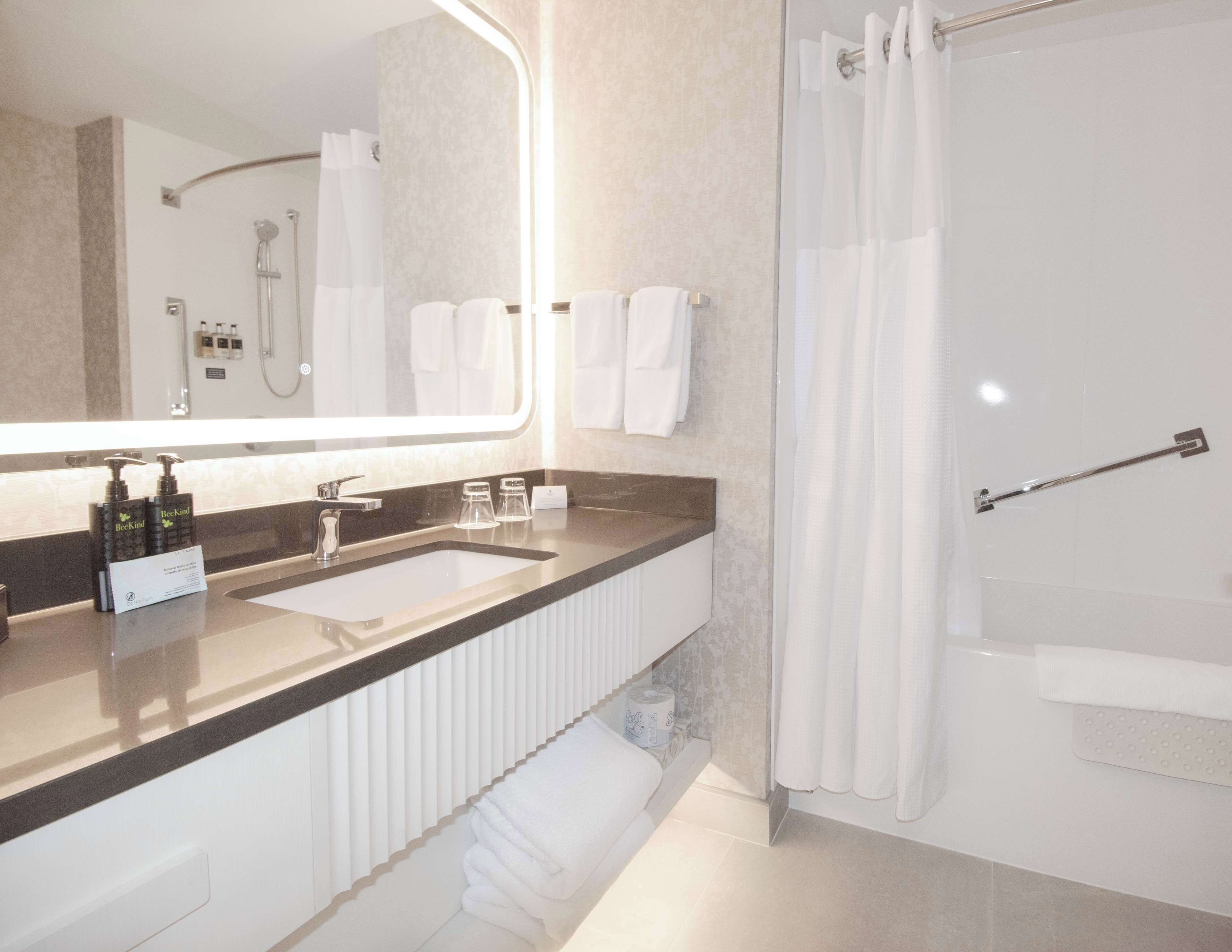 Un baño moderno con tocador de doble lavabo, un espejo grande, ducha con puerta de cristal y un perchero para toallas.