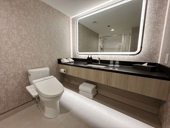 A modern bathroom with a toilet, sink, and mirror. - Coast Victoria Hotel & Marina by APA (Victoria)