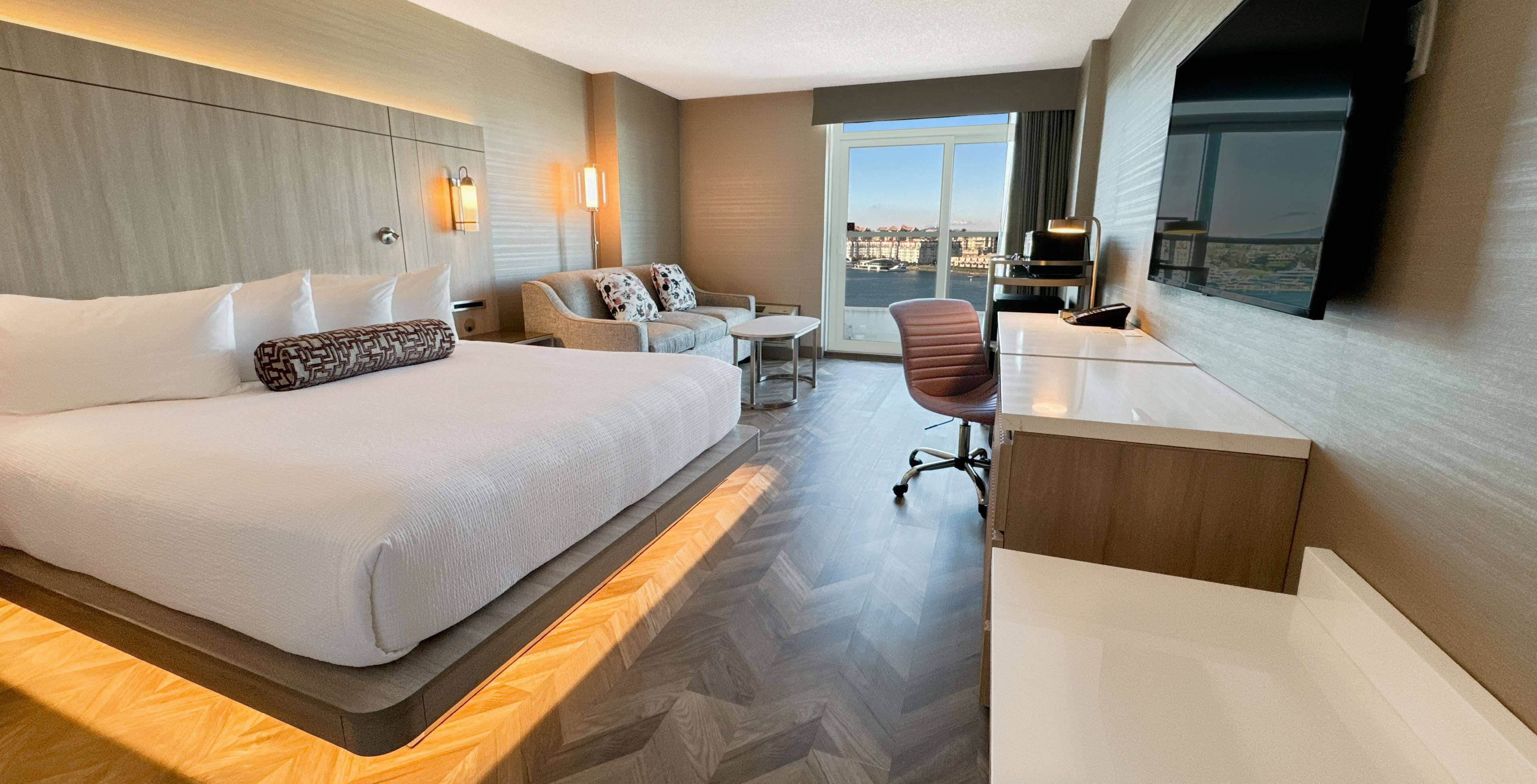 Habitación de hotel con una cama grande, un sofá, un escritorio y vistas a la ciudad.