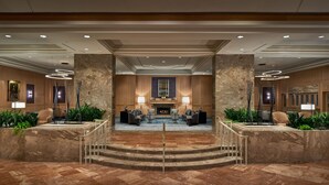 A grand lobby with a central fireplace, seating area, and marble flooring. - Westfields Marriott Washington Dulles (Chantilly)