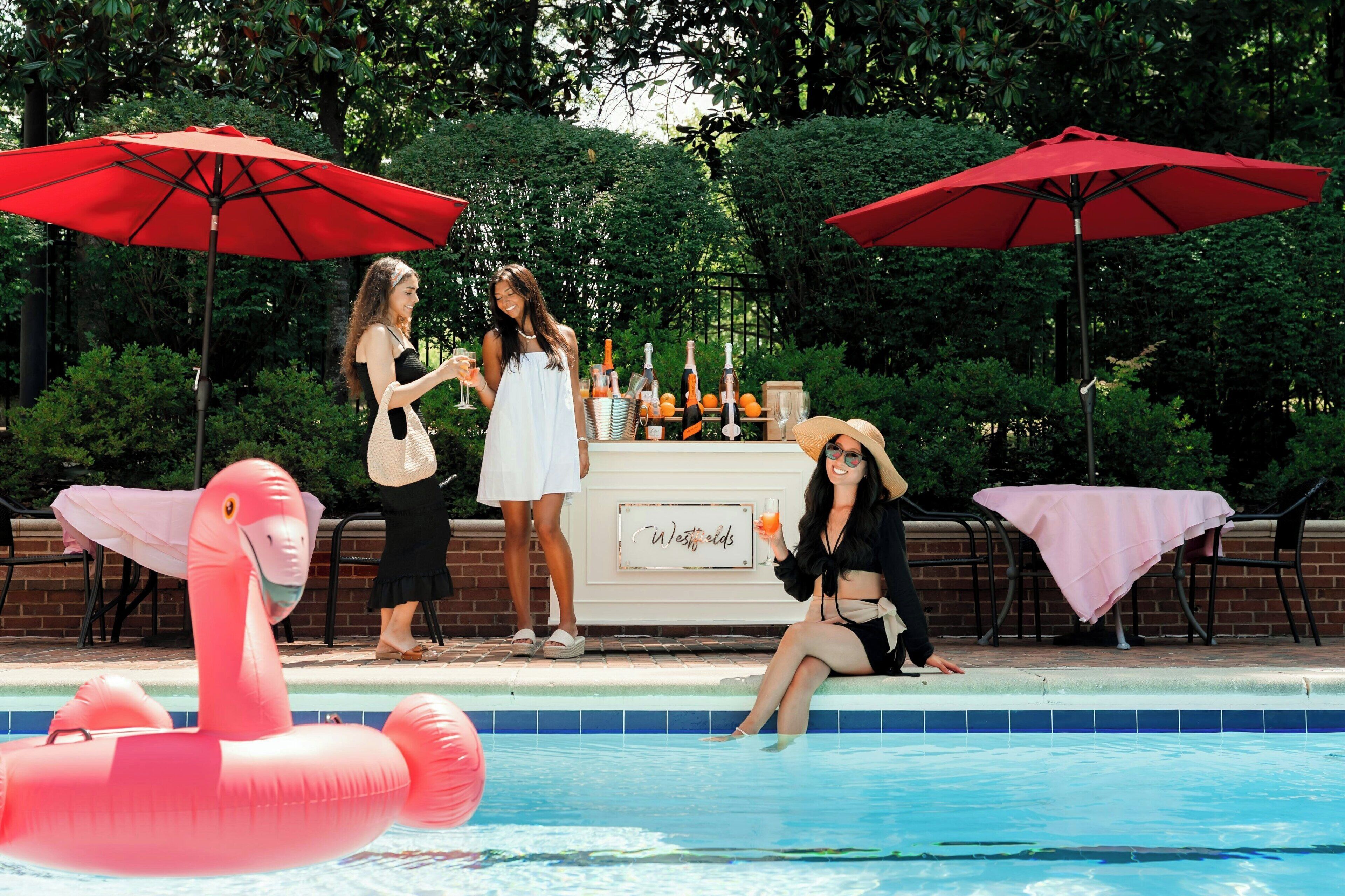 A poolside area with a bar setup, including bottles and glasses, and a flamingo float.