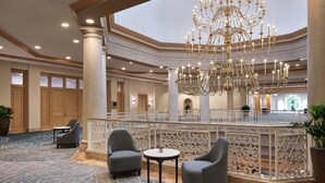 Un vestíbulo espacioso con una gran lámpara de candelabro, asientos cómodos y vistas al piso superior.