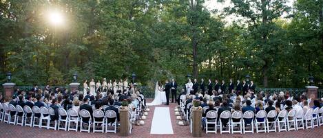 An outdoor wedding ceremony with guests seated in rows facing the aisle.