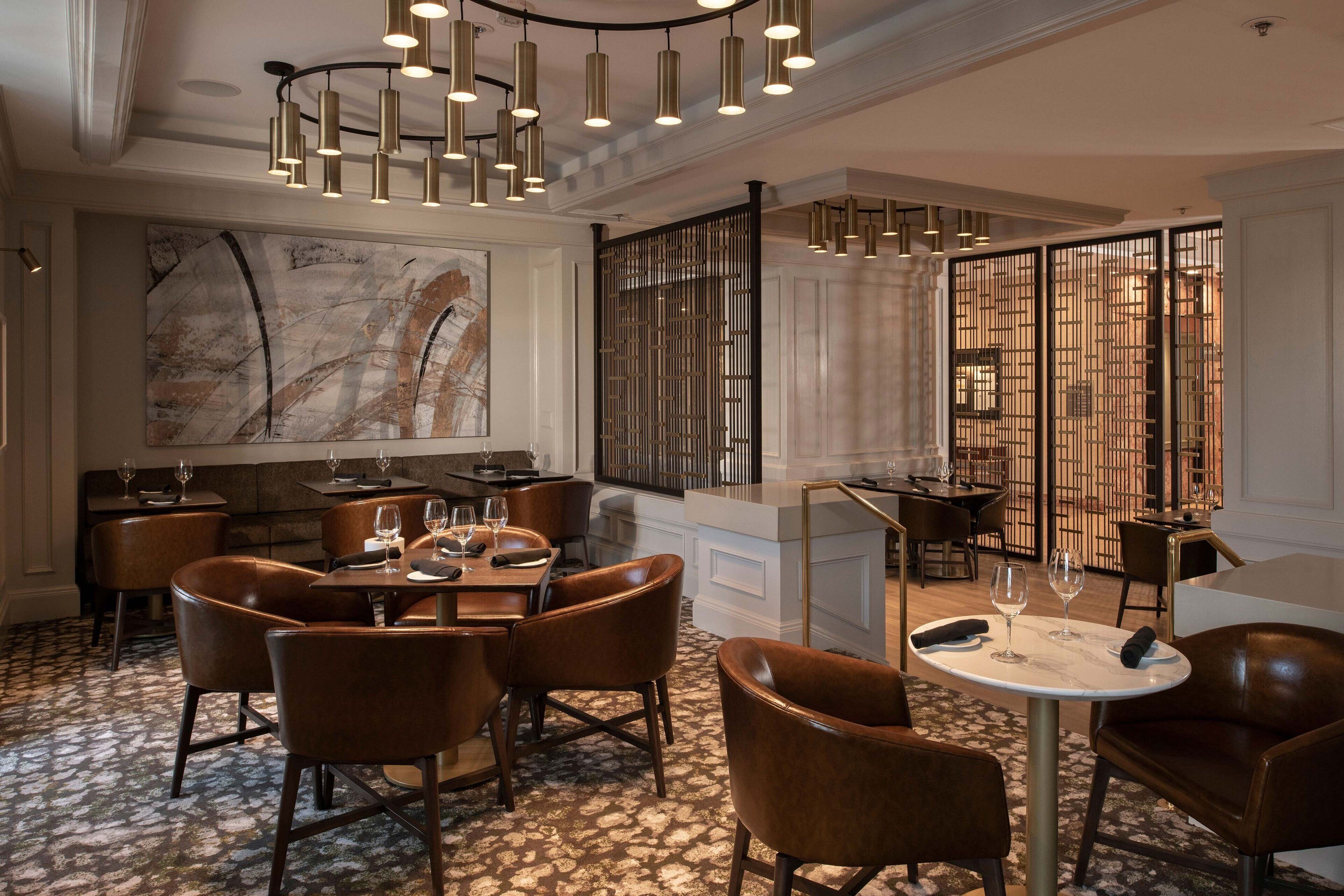 Un espace repas moderne avec des chaises en cuir, un sol en marbre et un grand tableau abstrait accroché au mur.
