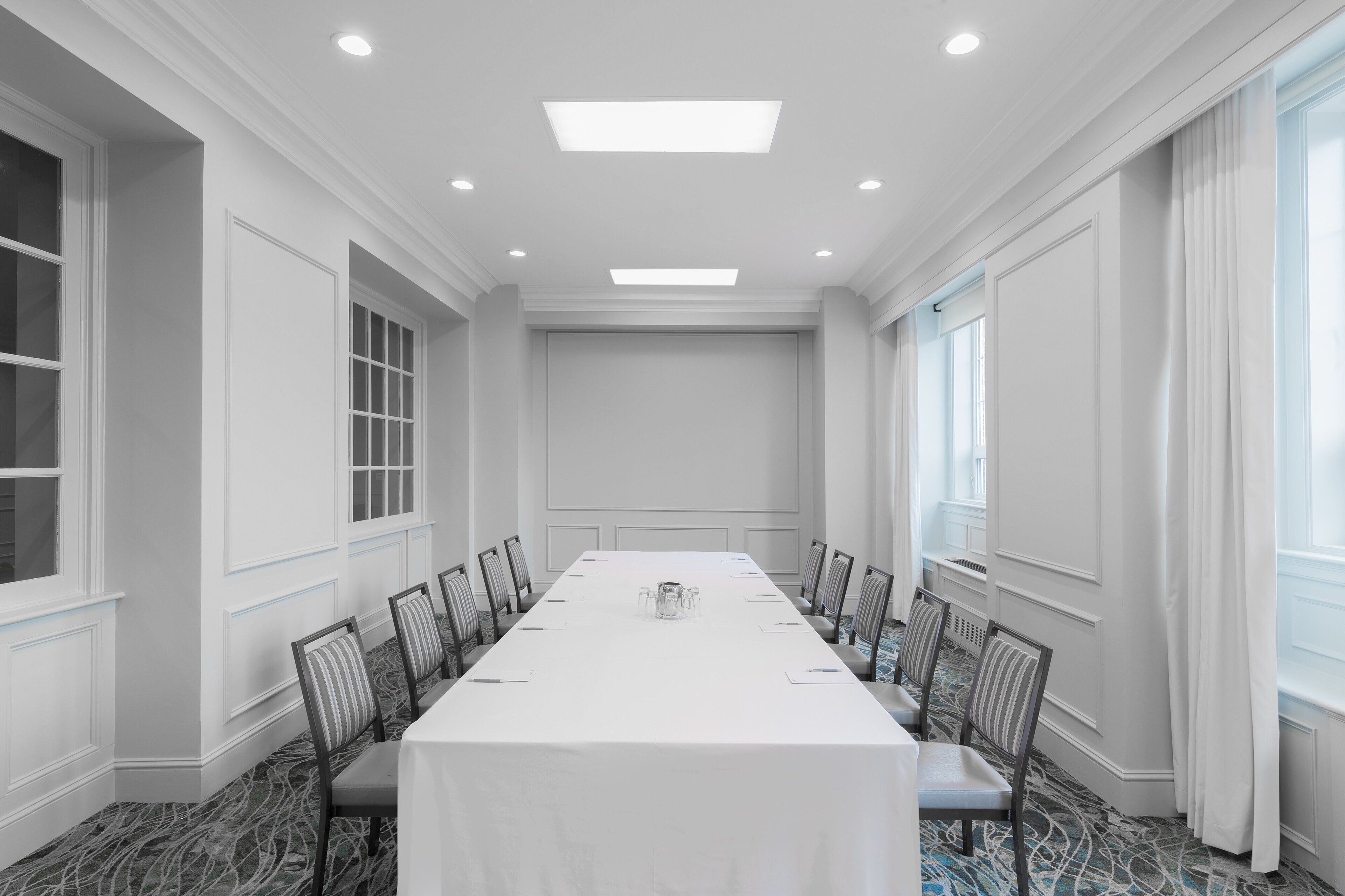 A conference room with a long table, chairs, and a chandelier.