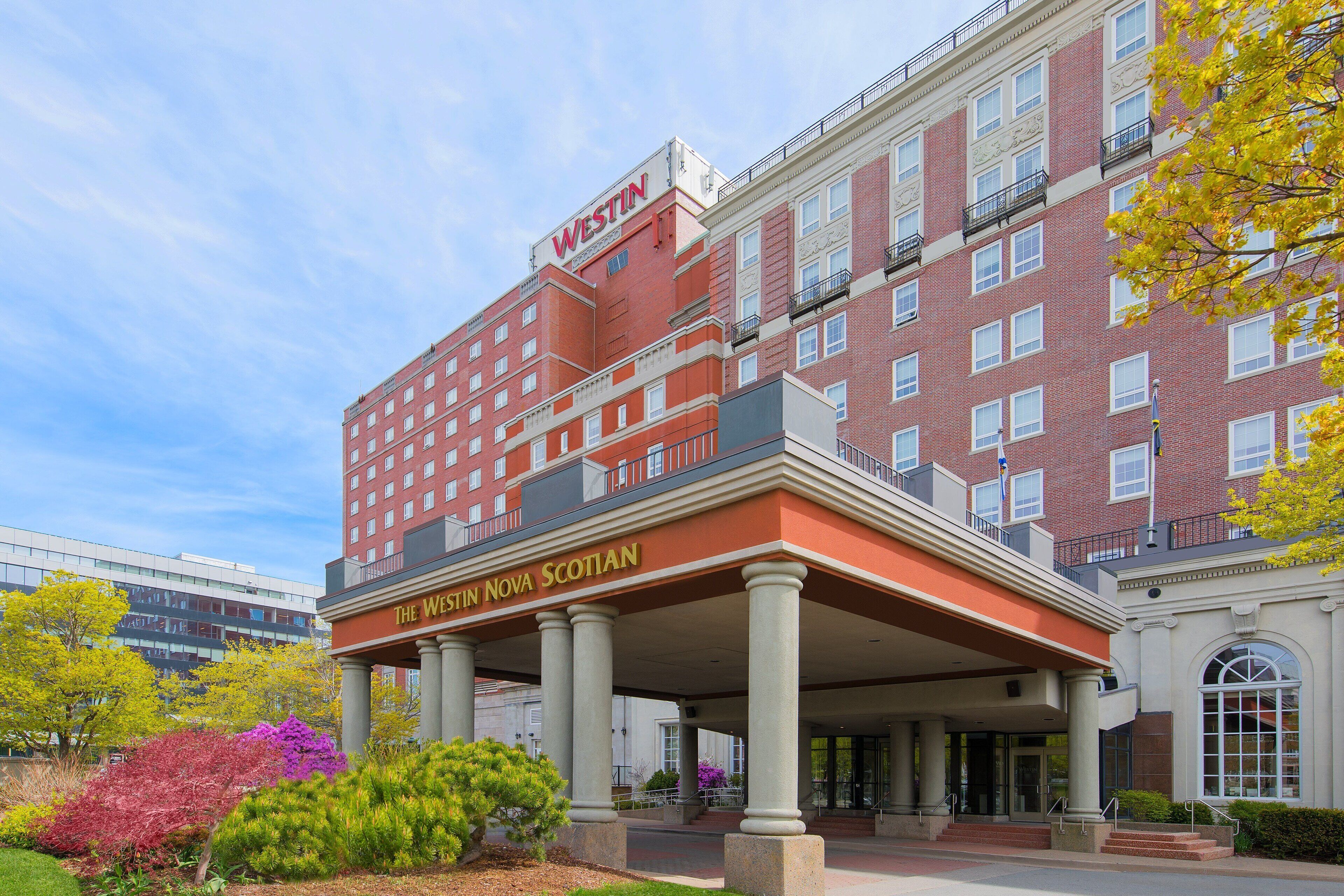 Un hotel de varios pisos con un llamativo letrero de "Westin", que presenta un estilo arquitectónico clásico con columnas y un balcón.