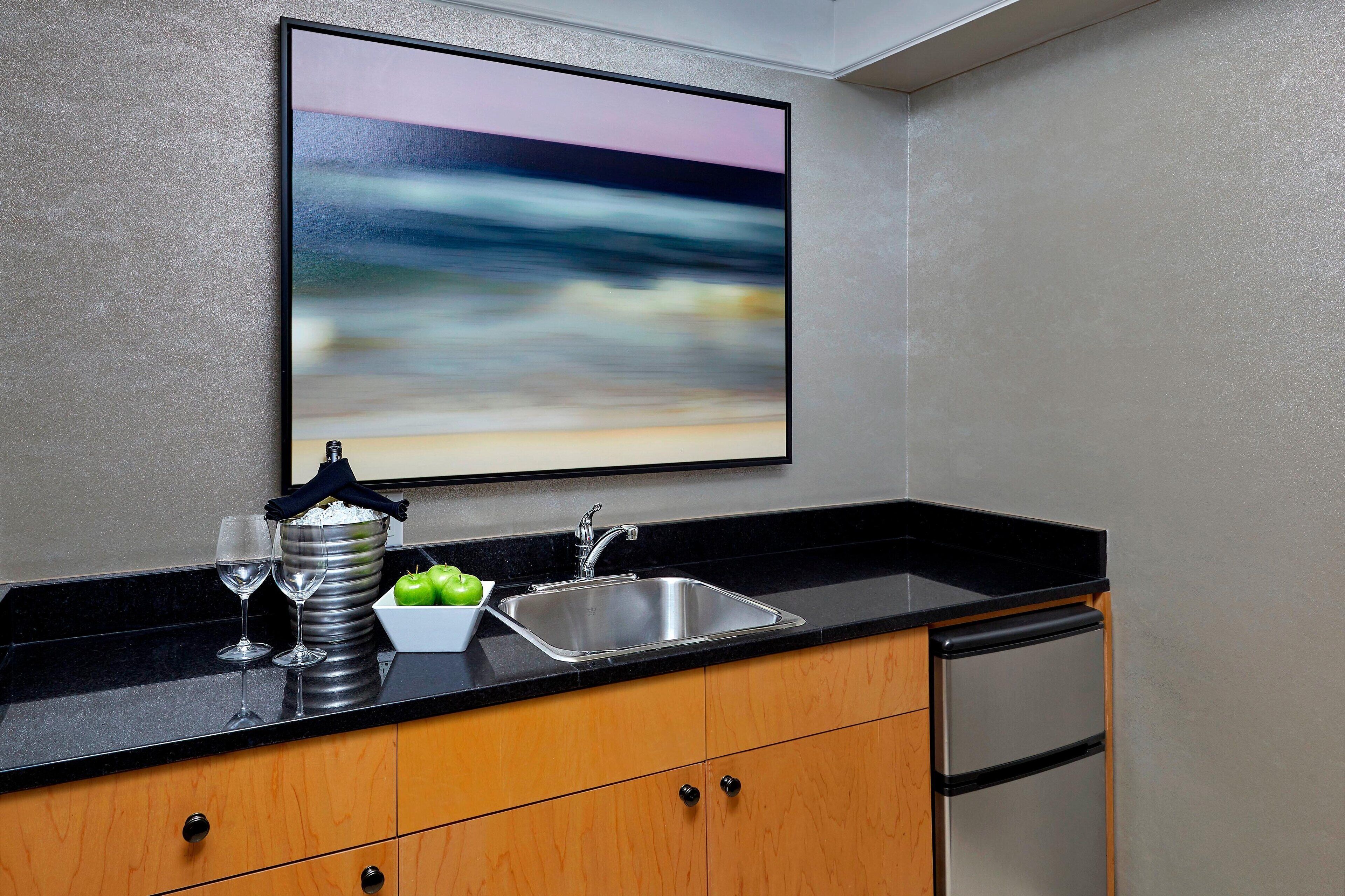 A kitchen with a stainless steel sink, wooden cabinets, and a black countertop.