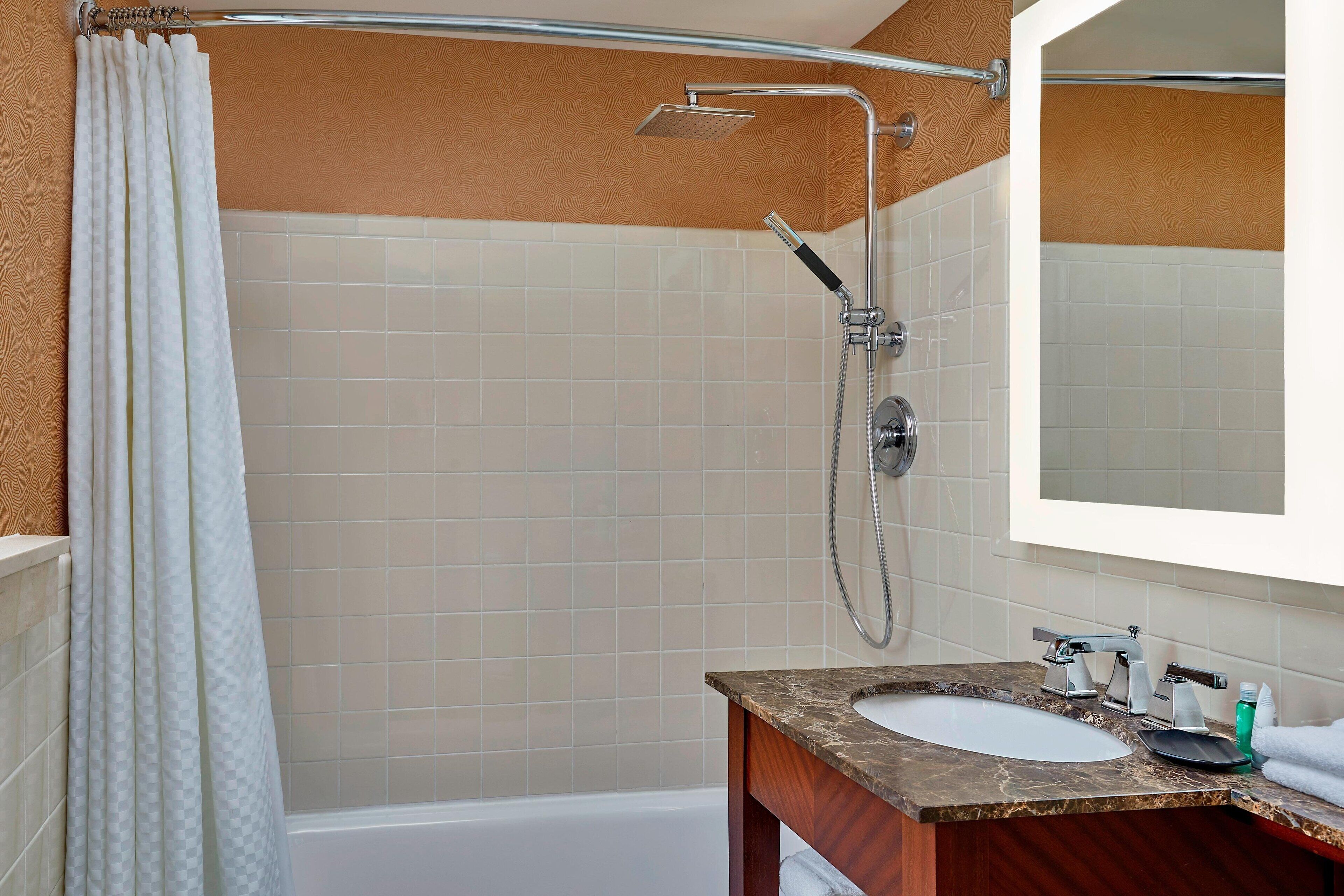 A bathroom with a bathtub, a shower, a sink, and a mirror.