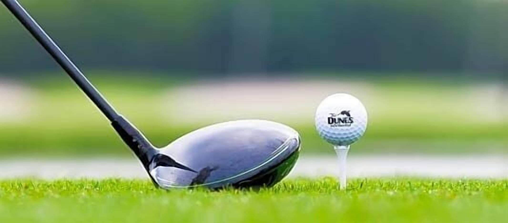 En golfklubba och en golfboll på en grön gräsmatta.