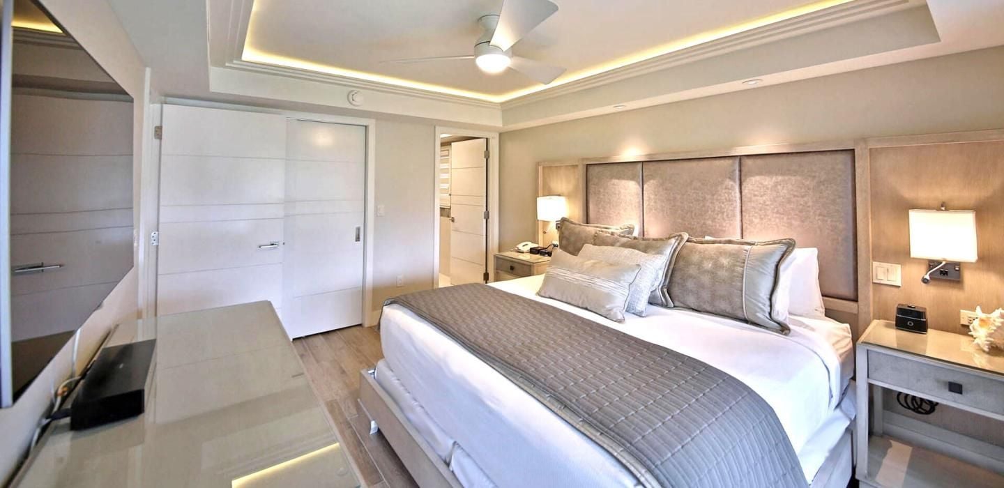Une chambre d’hôtel avec un grand lit, des lampes de chevet, une table de chevet et un ventilateur de plafond.