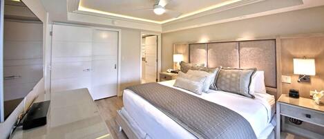 Une chambre d’hôtel avec un grand lit, des lampes de chevet, une table de chevet et un ventilateur de plafond.
