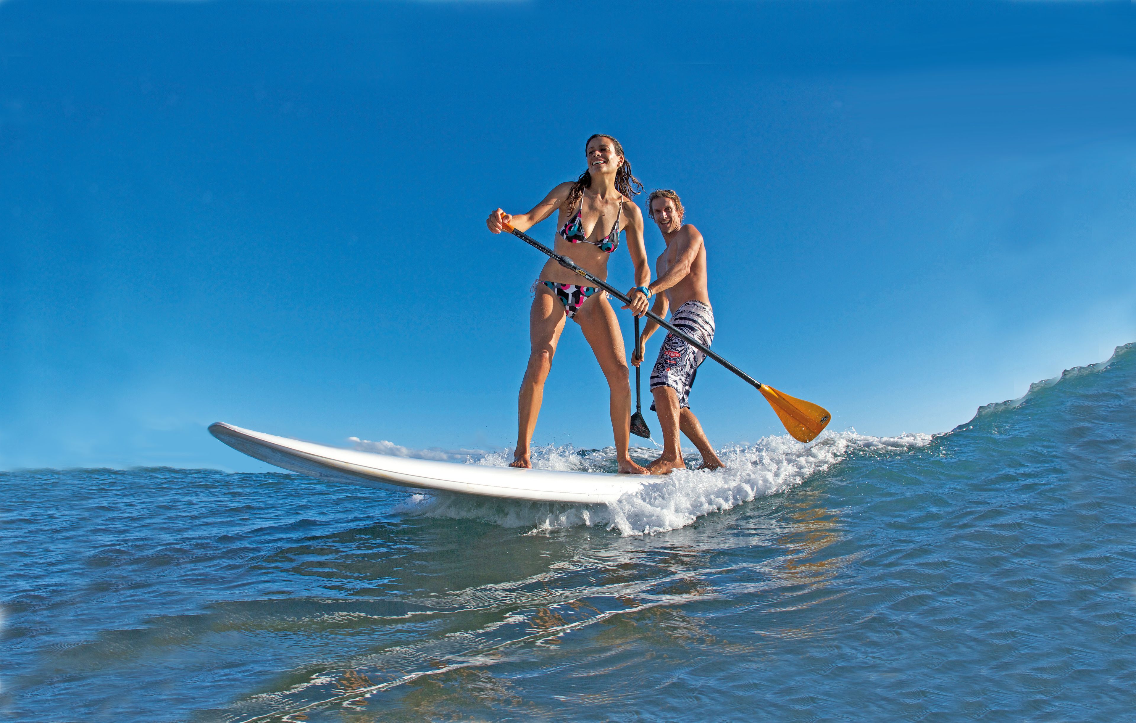 Deux personnes sur une planche de paddle, au large, dans l’océan.