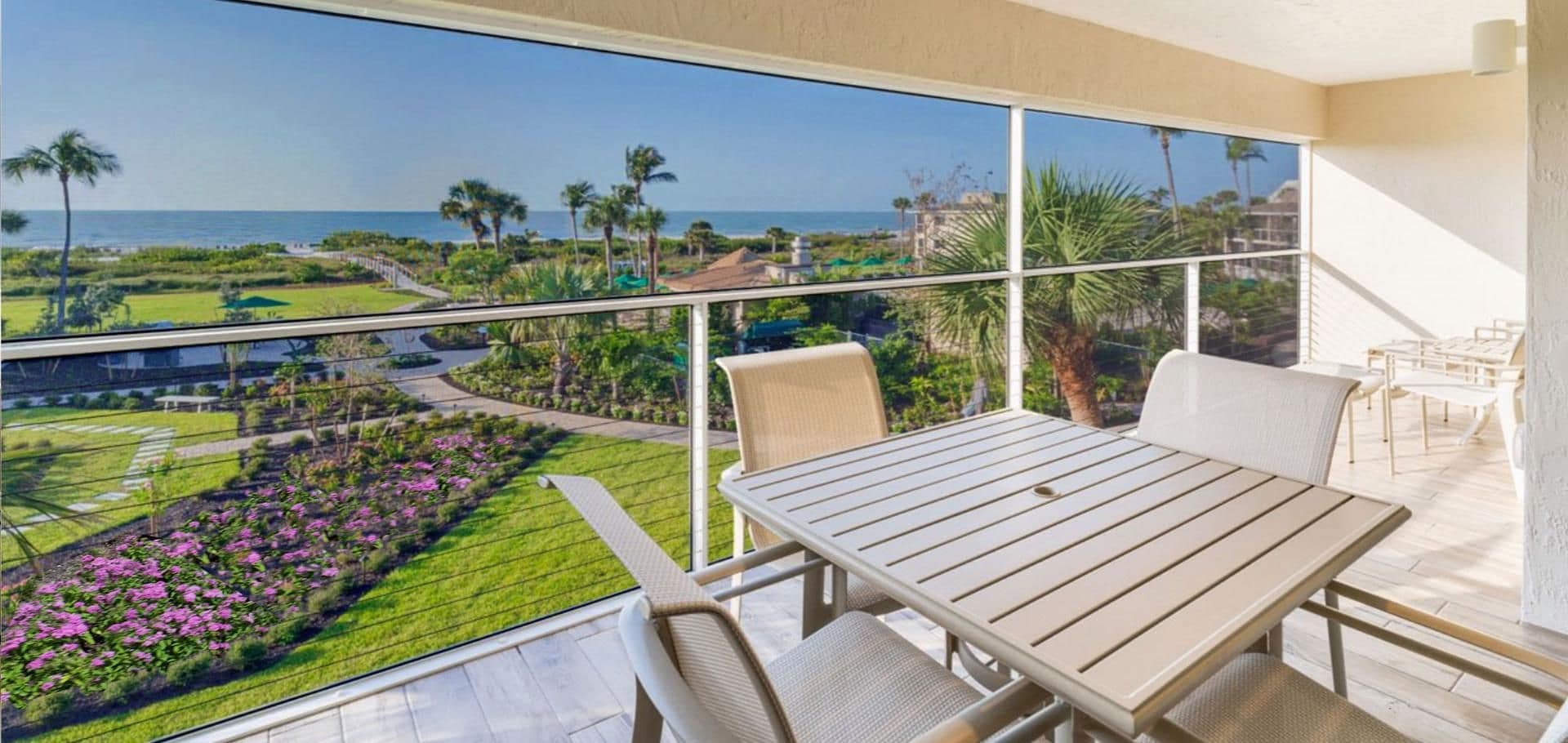 A balcony with a view of a landscaped garden and the ocean.