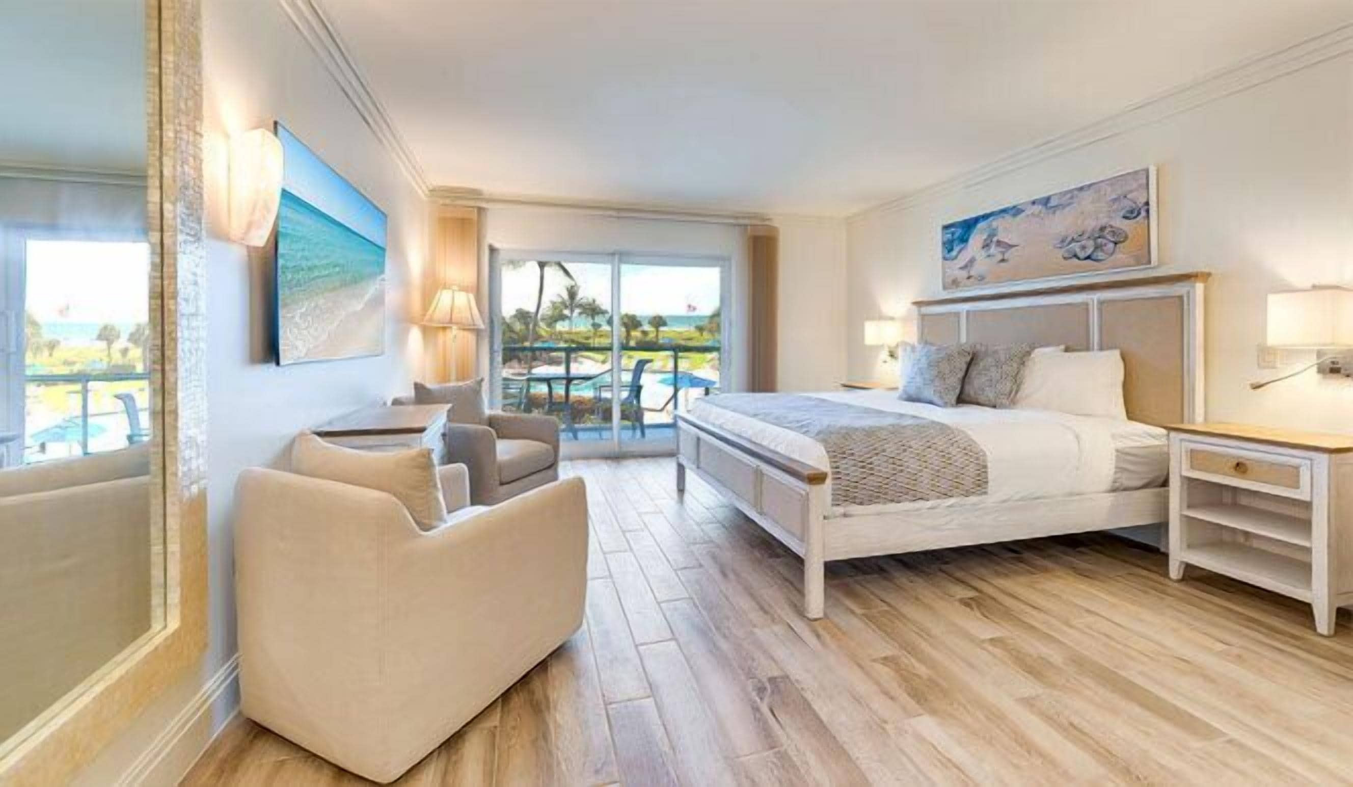 Quarto moderno com uma cama grande, um espaço de estar e uma varanda com vista.