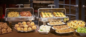 A buffet with various food items including pastries, fruits, and vegetables.
