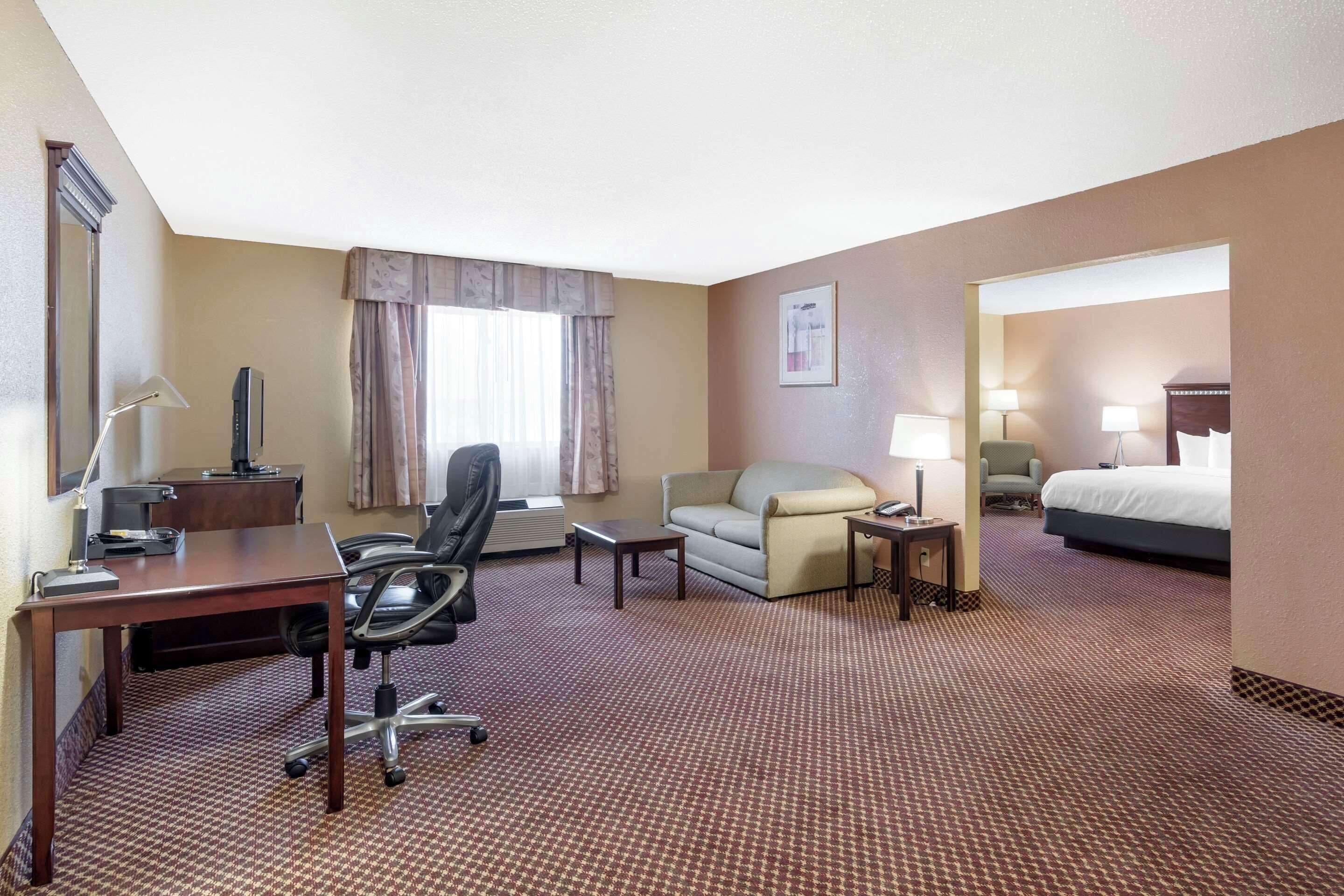A hotel room with a desk, office chair, sofa, and a bed.