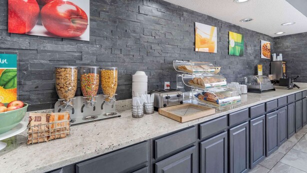 A breakfast bar with various food items, a coffee machine, and a fruit bowl.