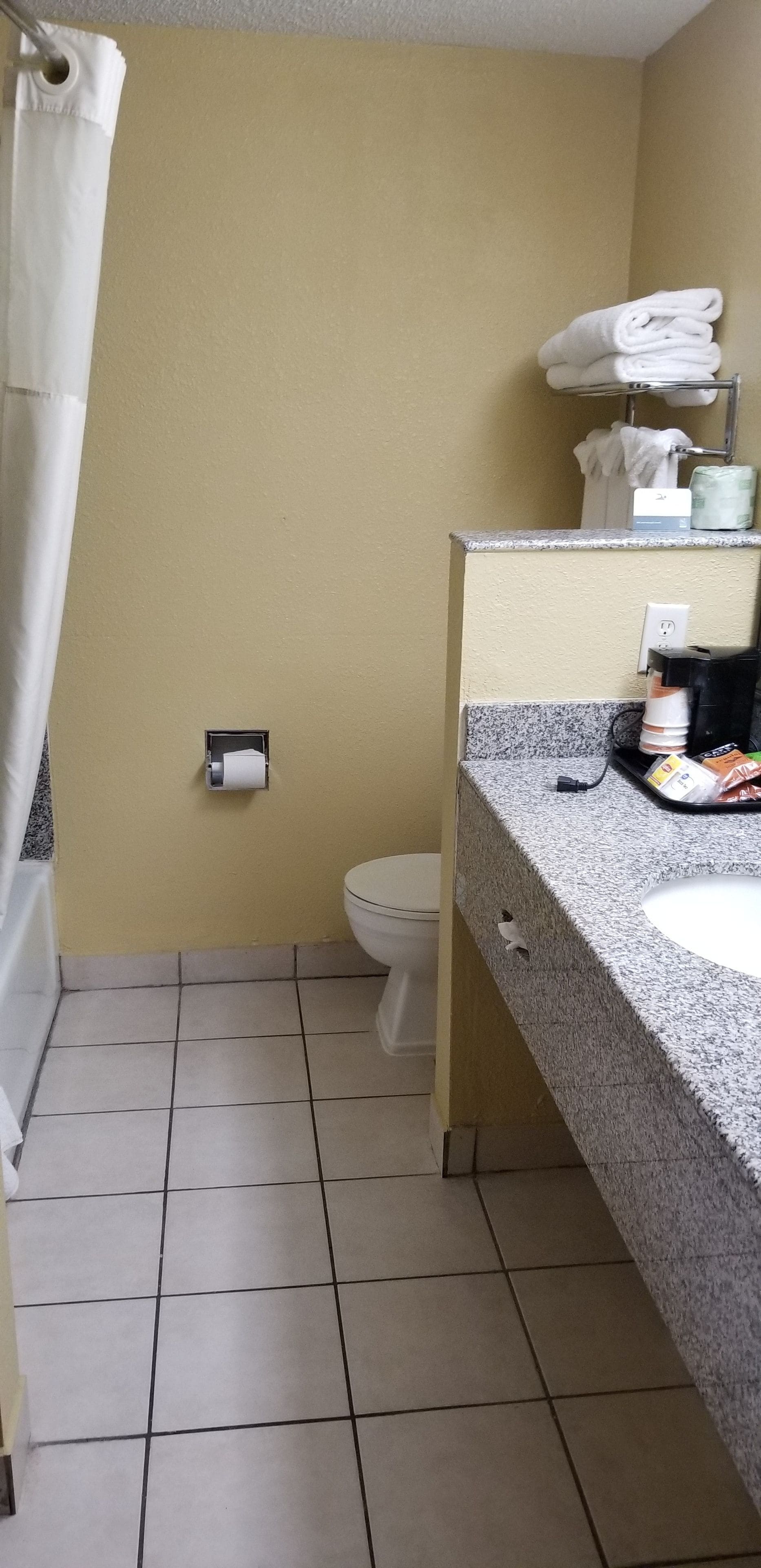 A bathroom with a toilet, a sink, a towel rack, and a paper towel dispenser.