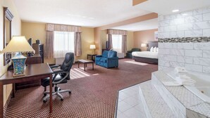 A hotel room with a desk, chair, sofa, and a large bed.