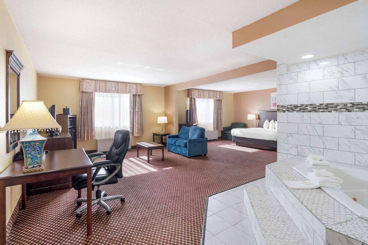 A hotel room with a desk, chair, sofa, and a large bed.