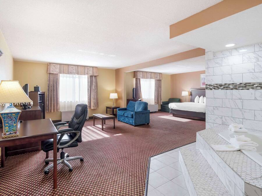 A hotel room with a desk, chair, sofa, and a large bed.