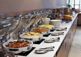 A buffet setup with multiple serving stations, including bowls of various foods and stacked plates.