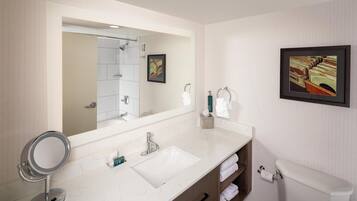 A bathroom with a large mirror, a sink, a toilet, and a framed picture on the wall.