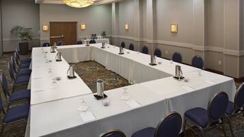 A conference room with a long table, chairs, and a small plant.