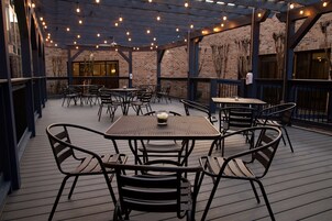 An outdoor patio area with tables and chairs, brick walls, and string lights.