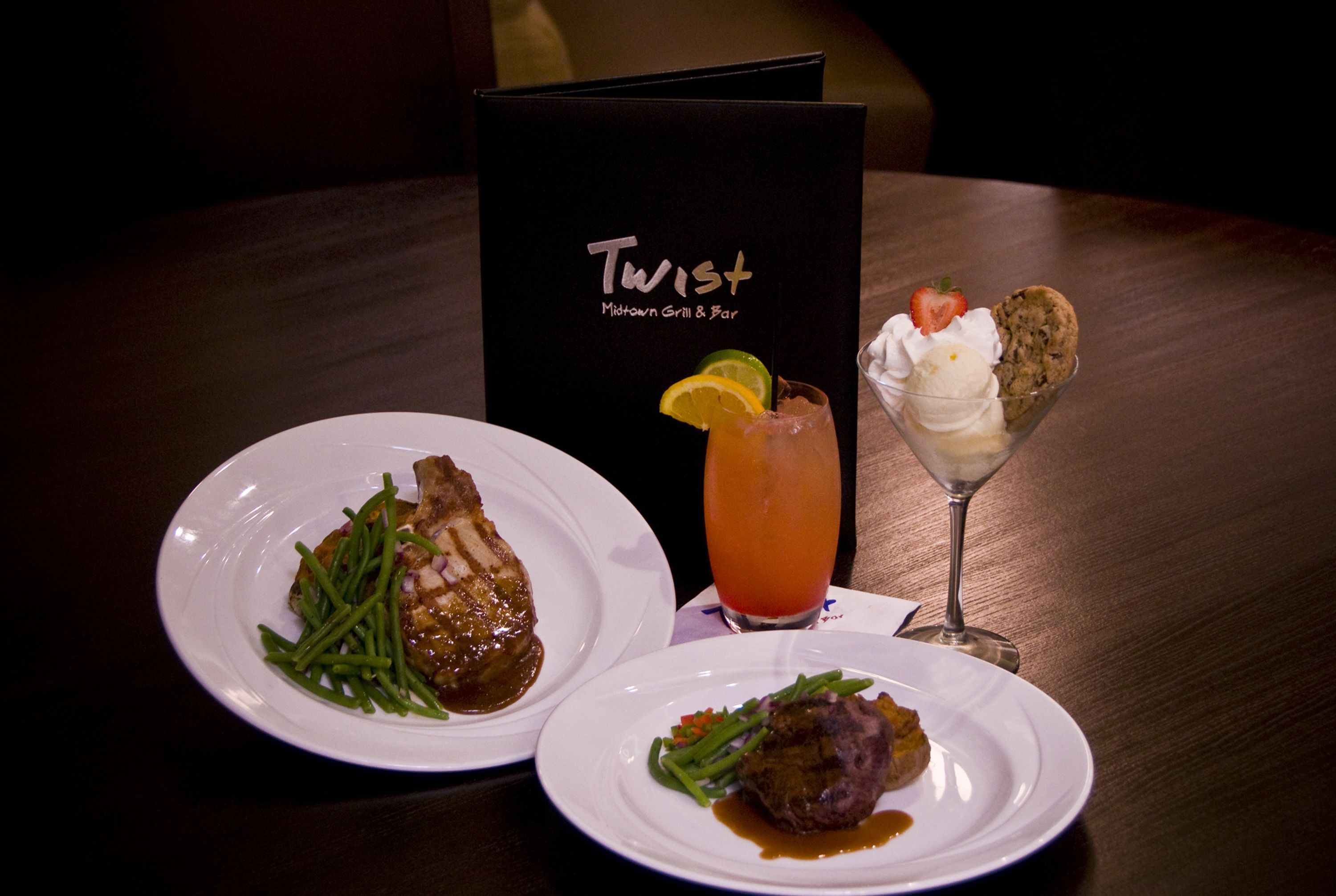 Een menukaart met de naam 'Twist Midtown Grill & Bar', met twee borden eten en een drankje.