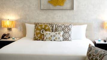 A hotel room with a bed, two bedside tables, a phone, a water bottle, and a framed artwork on the wall.