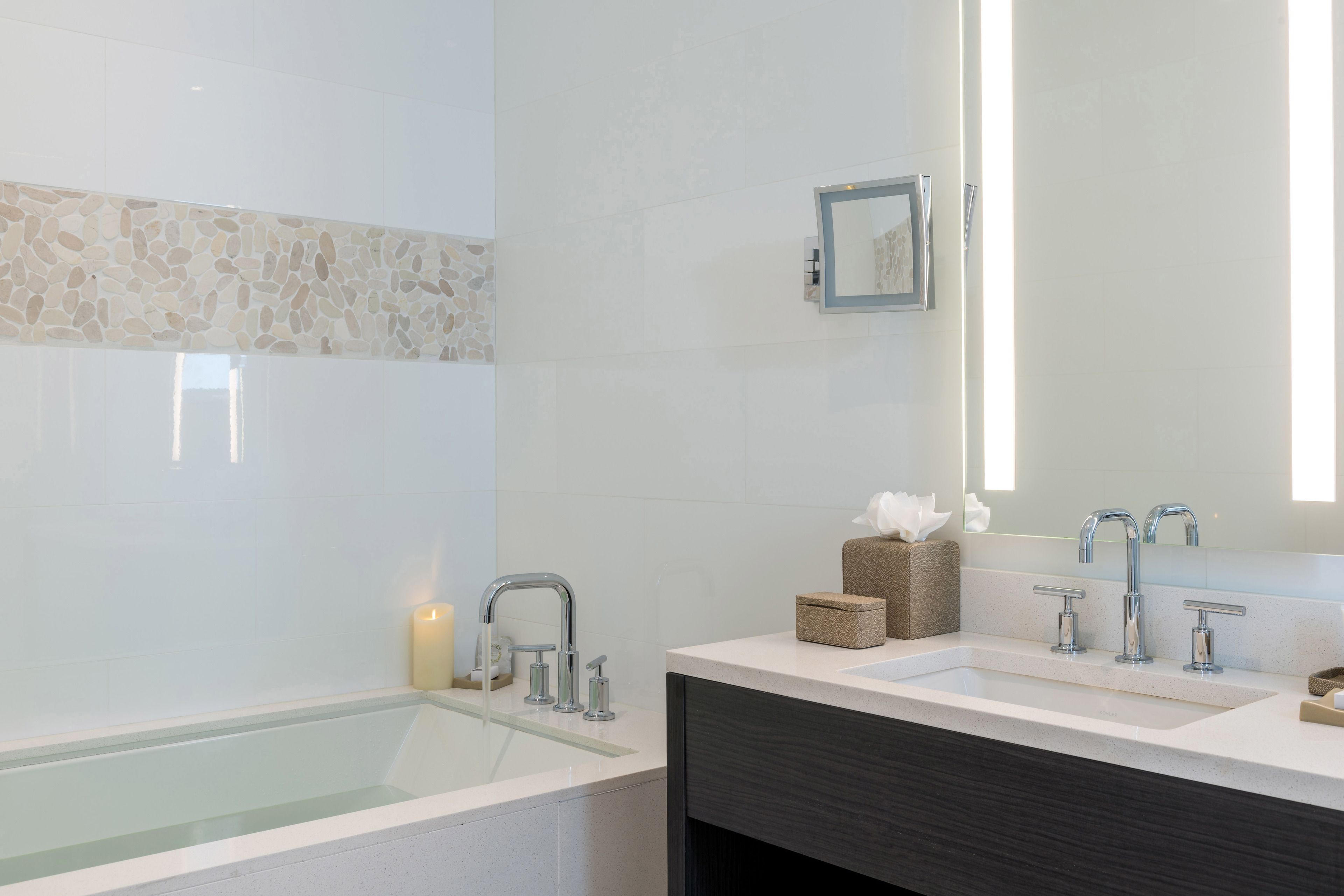 Une salle de bain moderne avec une baignoire, un meuble-lavabo avec un miroir et un porte-serviettes.