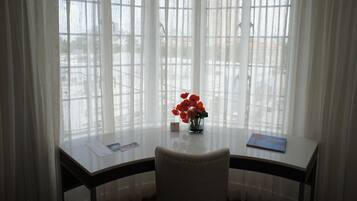 Ein Zimmer mit Tisch, Stuhl und einem Fenster mit transparenten Vorhängen.