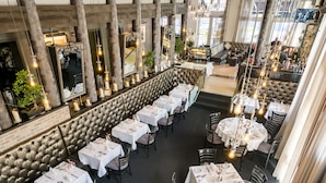 Un restaurant amb diverses sales de dinar, incloent-hi una barra i una zona de seients amb un sostre alt i parets de maó a la vista.