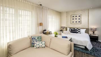 A hotel room with a sofa, a bed, a nightstand, and a wall-mounted artwork.
