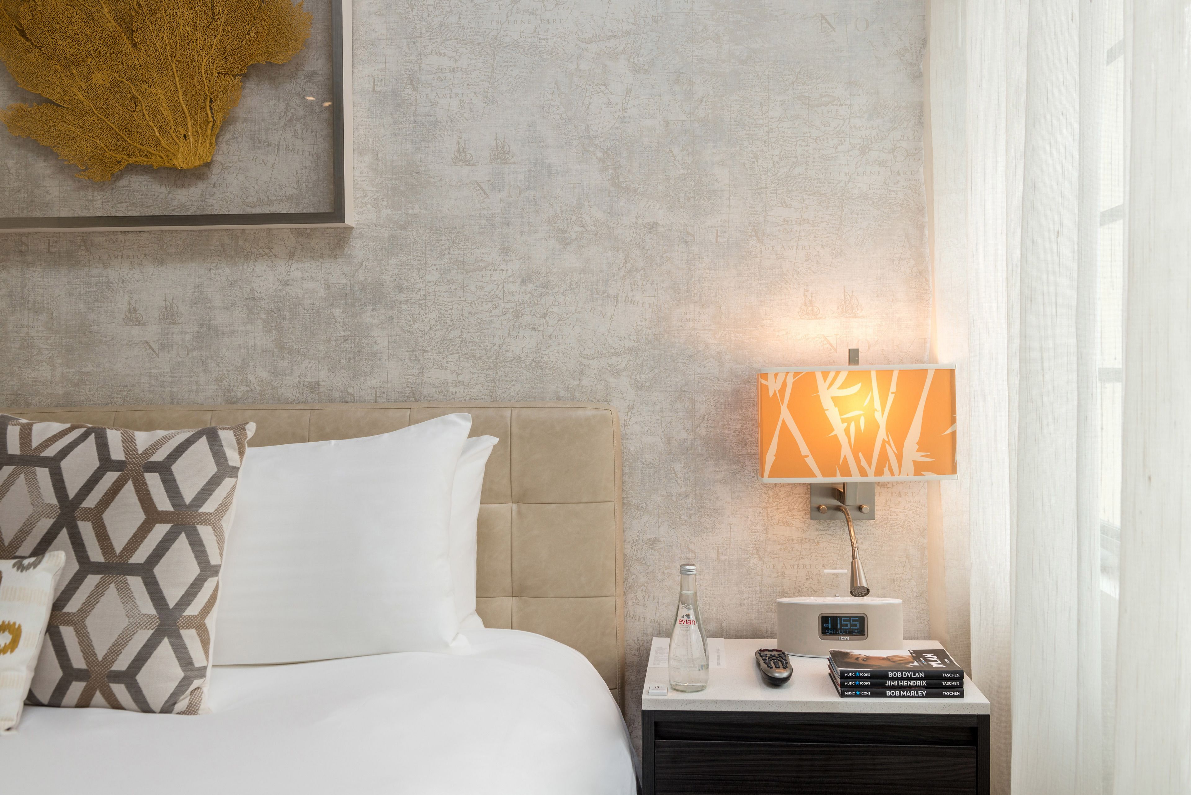 A hotel room with a bed, a nightstand with a lamp, a remote control, and a digital clock.