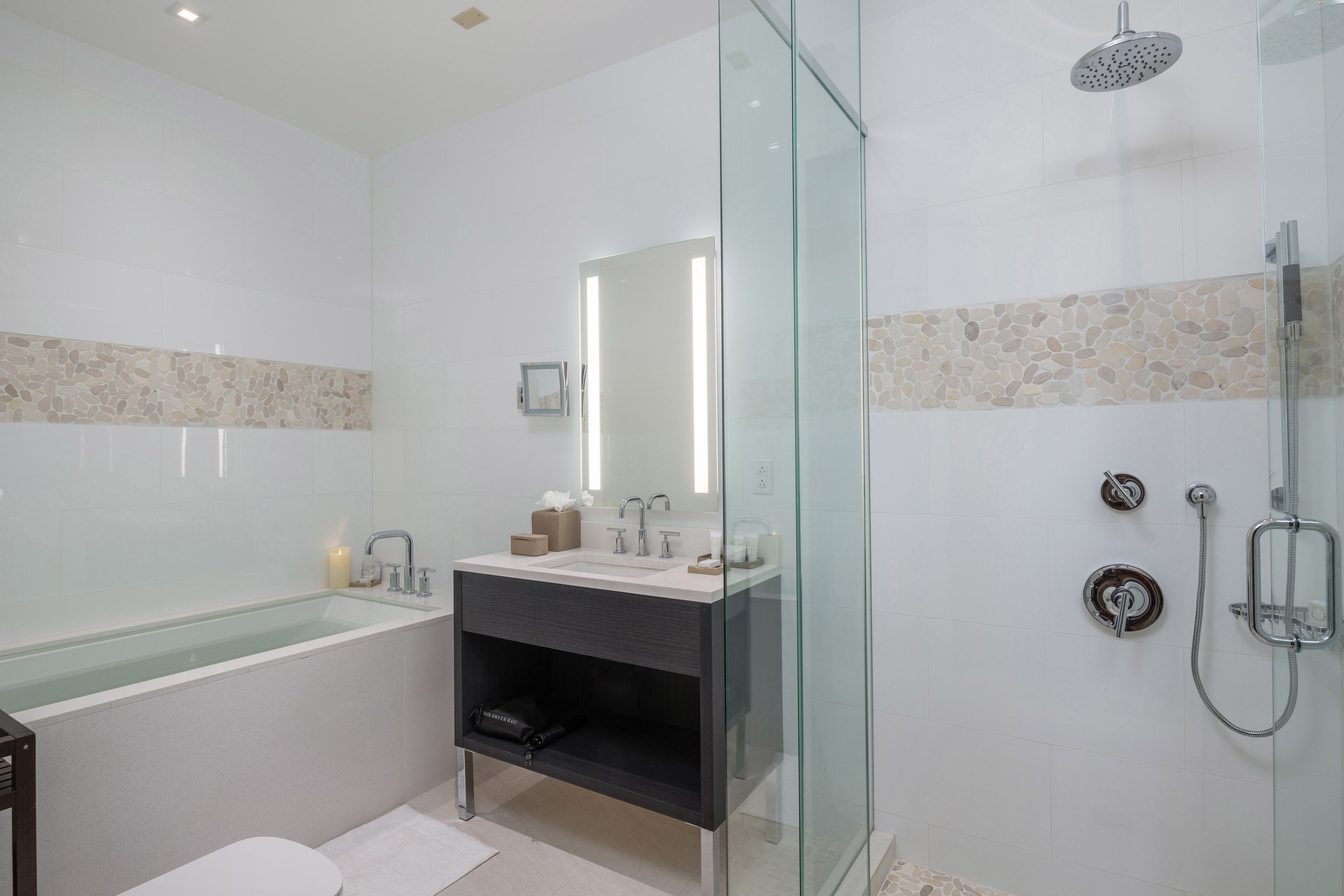 A modern bathroom with a glass-enclosed shower, a freestanding bathtub, and a vanity with a mirror.