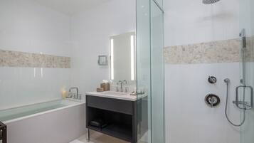 A modern bathroom with a glass-enclosed shower, a freestanding bathtub, and a vanity with a mirror.