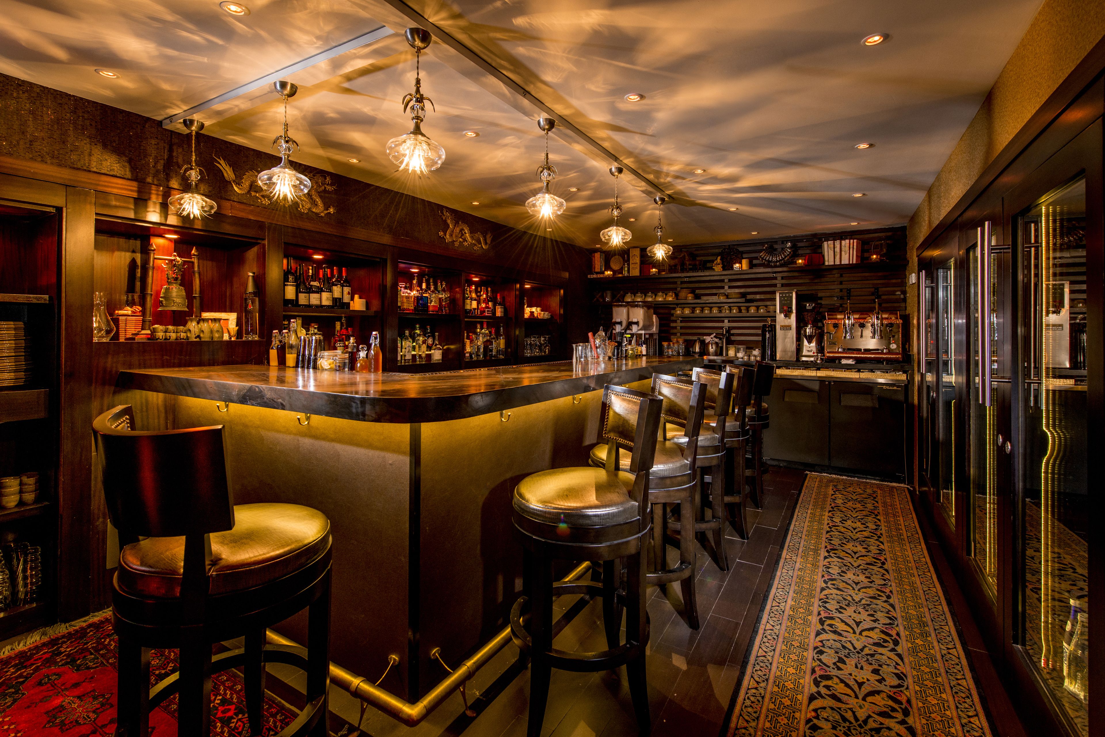 Een bar met een toog, krukken en een vloerkleed met dessin.