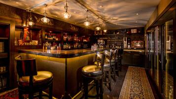 Een bar met een toog, krukken en een vloerkleed met dessin.