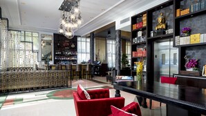 Un vestíbul espaiós amb una zona de bar, cadires tapissades de color vermell i un gran taulell de recepció negre.